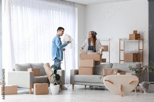 Young couple packing things in living room on moving day
