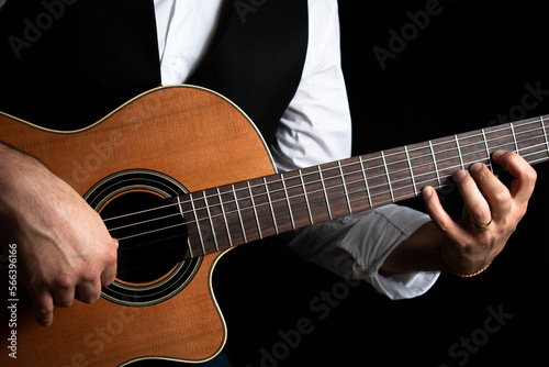 Hombre elegante vestido con chaleco y camisa, tocando la guitarra clásica