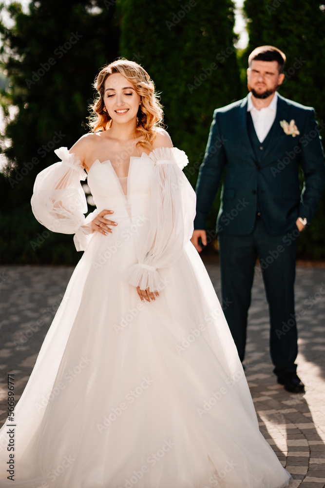 a bride in a delicate dress stands in front of the groom in the park. a bride in a delicate dress stands in front of the groom in the park.