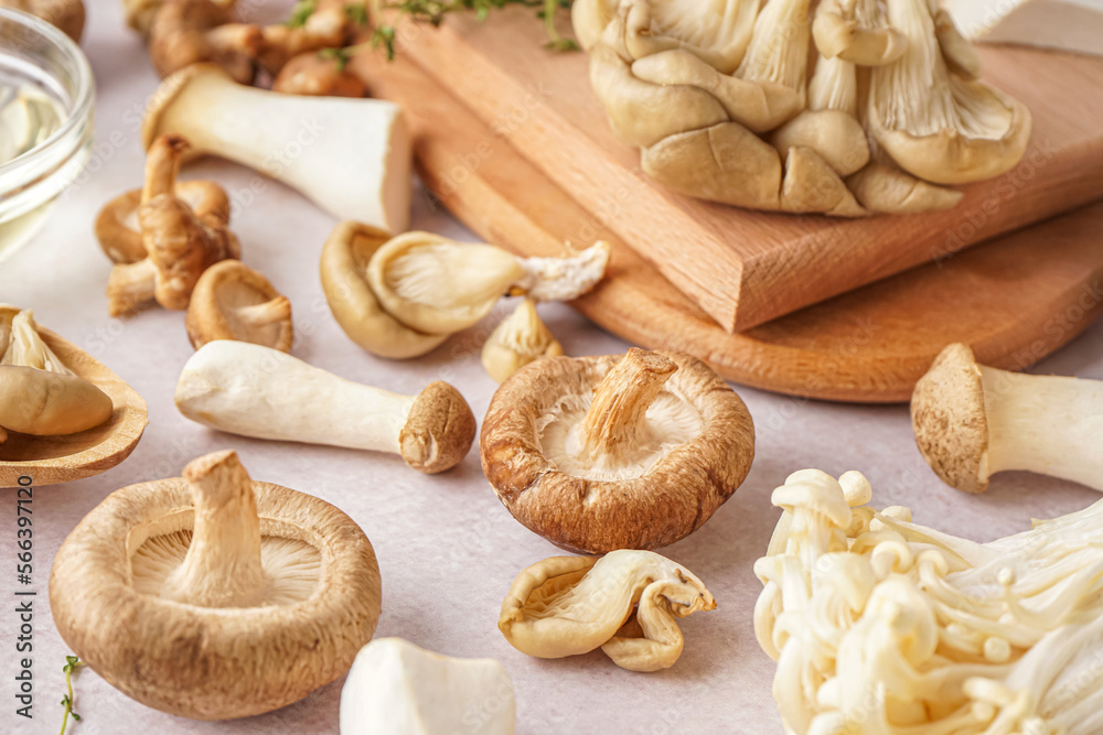 Fototapeta premium Assorted fresh culinary mushrooms on white background with wooden boards and oil, healthy ingredient for cooking, wooden cutting boards and a small bowl of oil are visible in the composition