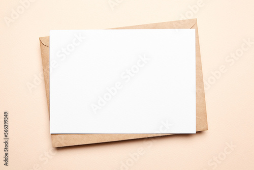 Greeting card mockup with envelop on beige background, top view, flat lay. Blank holiday card or flyer
