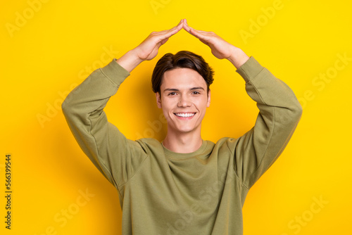 Photo of positive friendly person arms demonstrate roof gesture above head isolated on yellow color background
