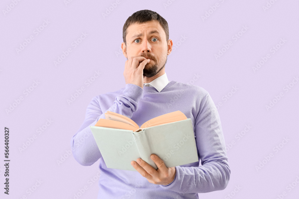 Handsome man with book biting nails on lilac background Handsome man with book biting nails on lilac background