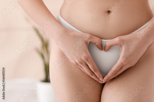 Fotobehang Young woman in panties making heart shape with hands at home, closeup