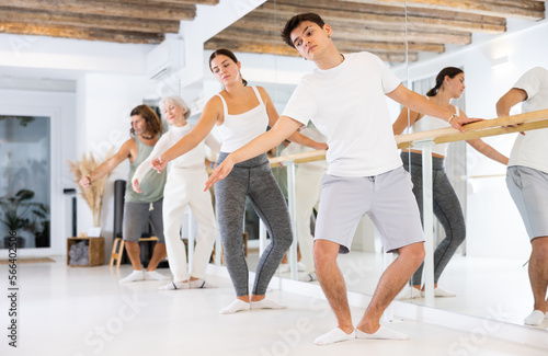 Group of sports people doing exercises at ballet barre