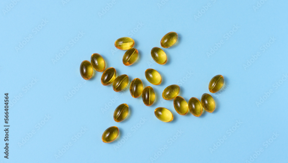 Yellow capsules with fish oil on a blue background, top view Yellow capsules with fish oil on a blue background, top view