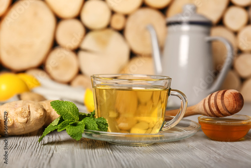 Cup of tea with mint, ginger and honey on grey wooden table, closeup