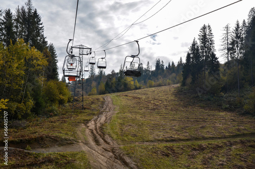 Empty сhairlift on a fall mountain slope with colorful trees. Elevator in the autumn season. Carpathian Mountains, Ukraine