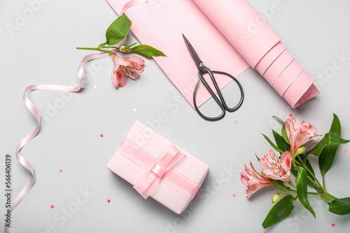 Composition with gift box, wrapping paper, scissors and alstroemeria flowers on light background. Women's Day celebration