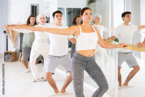Group of sports people doing exercises at ballet barre