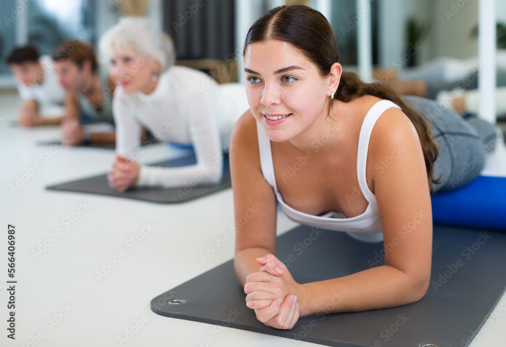 Young athletic woman performs exercises with roller in the gym