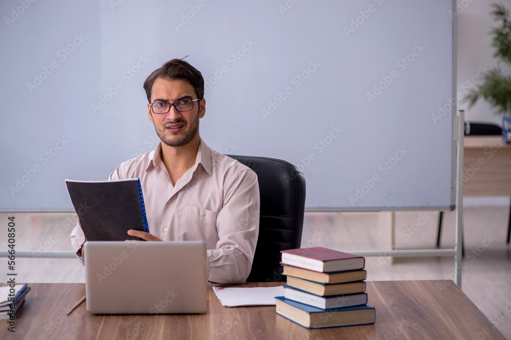 Young male teacher sitting in the classroom Young male teacher sitting in the classroom