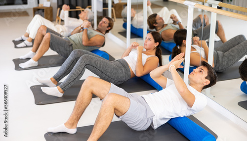 Group of different people performs sports exercises in fitness center