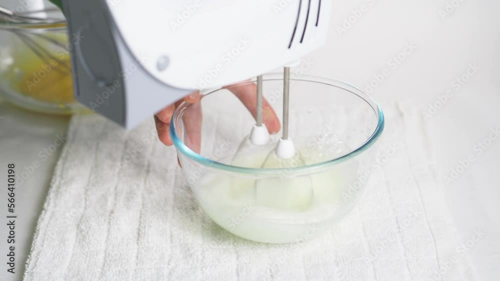 A man beats egg white with a mixer in a transparent bowl in the kitchen. Several spoons of sugar. High quality 4k footage A man beats egg white with a mixer in a transparent bowl in the kitchen. Several spoons of sugar. High quality 4k footage
