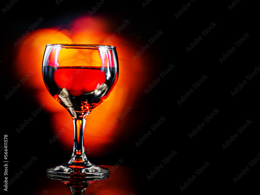 Glass or red wine, dark background with fire color light painting effect. Alcohol product for a special occasion.
