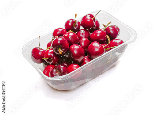 Plastic container full of red ripe cherries on white background. Produce product for sale in a market of shop.