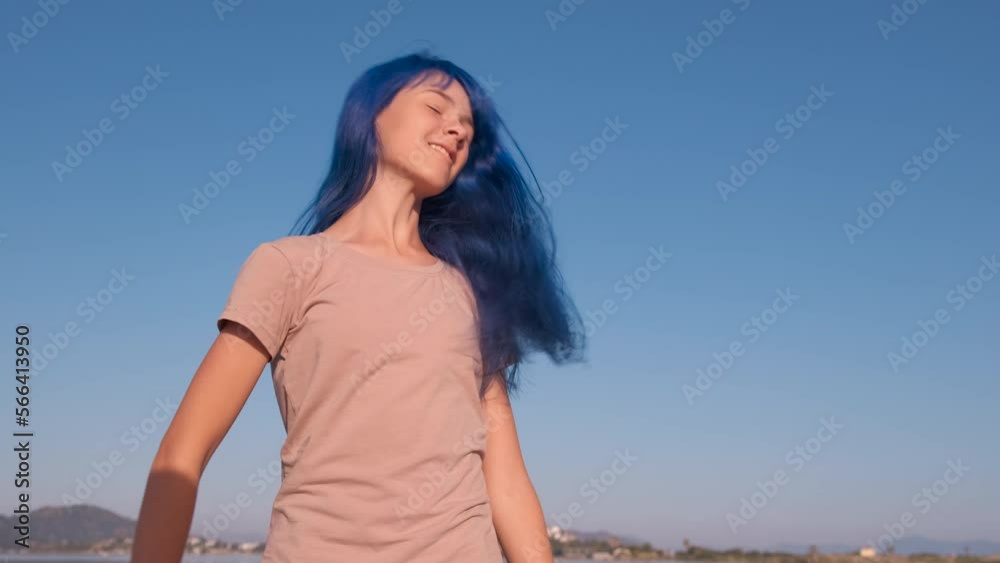 Alone teen traveler dance by sea. A pretty teen play and spinnig on the sea shore. A view of younger with dyed blue hair. Alone teen traveler dance by sea. A pretty teen play and spinnig on the sea shore. A view of younger with dyed blue hair.