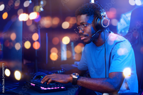 Concept internet web business security, trader man. Hacker American African with headphones working on computer with crypto stocks, neon color