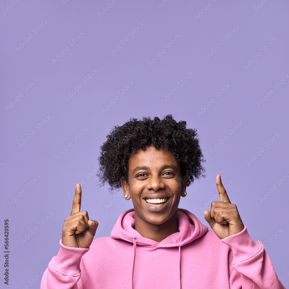 Smiling happy African teenager pointing fingers up presenting new promotion offer, showing ads at copy space for shopping promo, advertising product standing isolated on purple background. Close up Smiling happy African teenager pointing fingers up presenting new promotion offer, showing ads at copy space for shopping promo, advertising product standing isolated on purple background. Close up