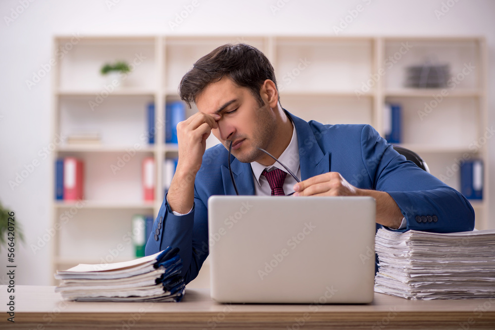 Young male employee and too much work in the office Young male employee and too much work in the office