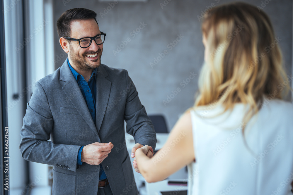 Business people shaking hands after successful meeting. Businessman And Businesswoman Shaking Hands In Office. Businessman shaking hands with his female partner celebrating successful teamwork. - obrazy, fototapety, plakaty 