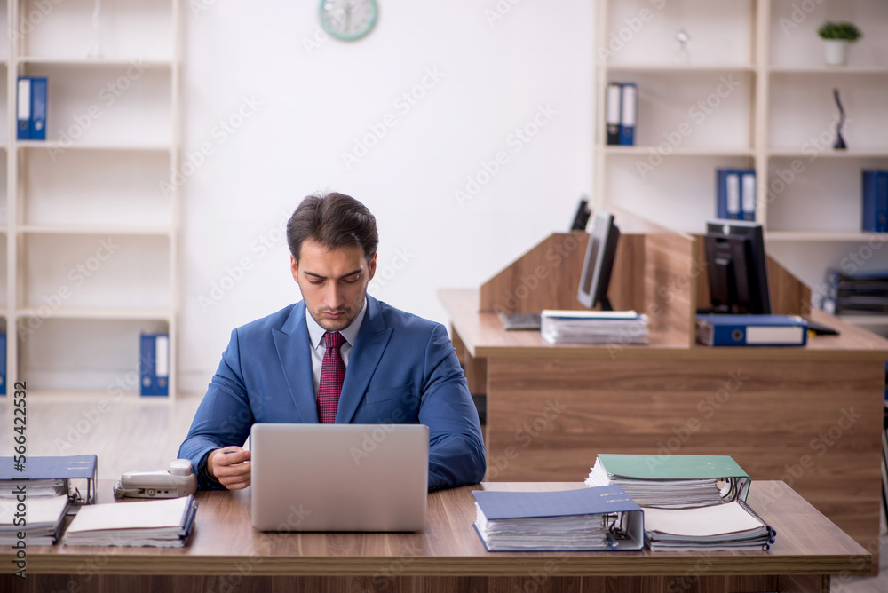 Young male employee unhappy with excessive work in the office Young male employee unhappy with excessive work in the office