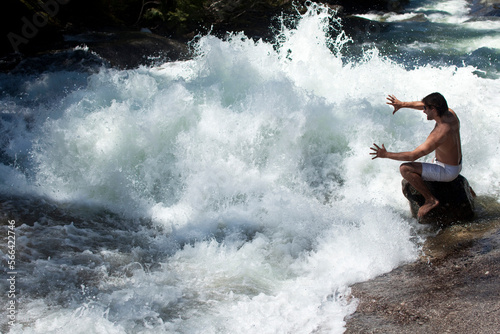 A young man manipulates the water of a raging river in Idaho.