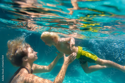 Mother and son swimming underwater in swimming pool photo