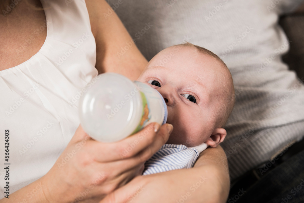 Close -up of baby boy bottle feeding by his mother Close -up of baby boy bottle feeding by his mother