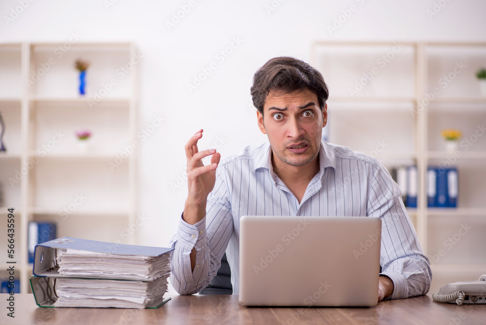 Young male employee and too much work in the office Young male employee and too much work in the office
