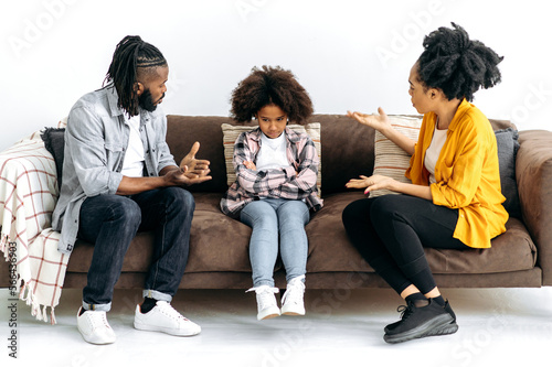 Fotografía African American parents sort things out with their preschool daughter, yell at her, child resenting parents