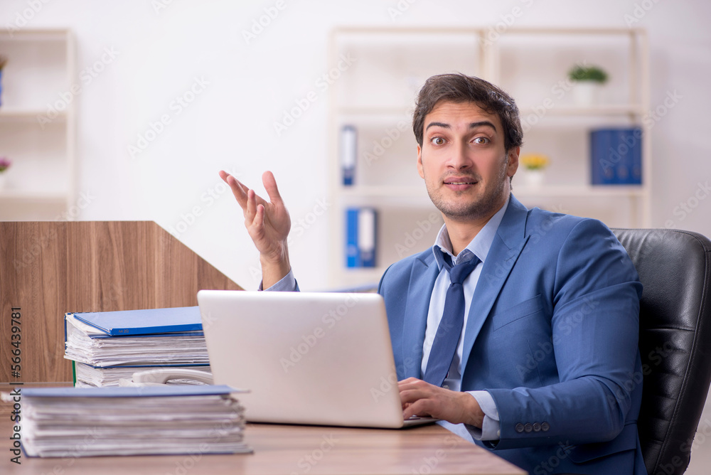 Young male employee and too much work in the office Young male employee and too much work in the office