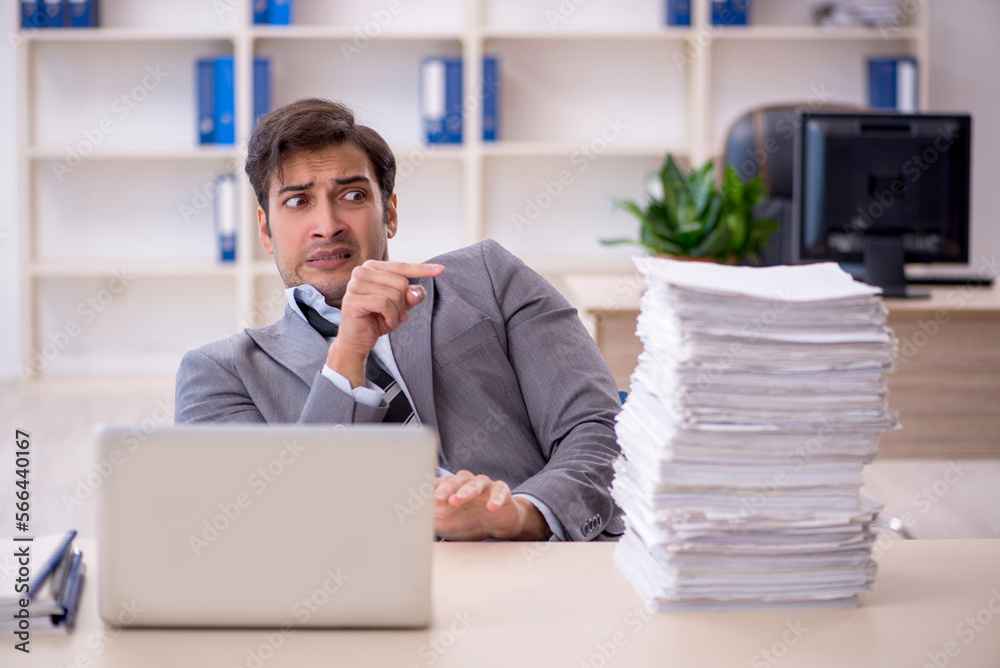 Young male employee and too much work in the office Young male employee and too much work in the office