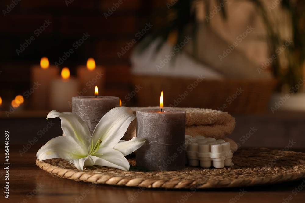 Spa composition with burning candles, lily flower and towels on wooden table in wellness center Spa composition with burning candles, lily flower and towels on wooden table in wellness center