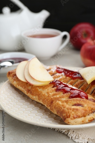 Fresh tasty puff pastry with jam and apples on white textured table, closeup