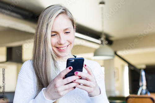 young adult pretty blonde woman using a smartphone