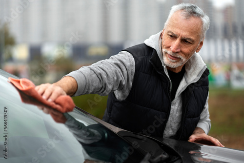 Car detailing. Caucasian senior man using microfiber cloth, polishes the car. Auto service and wash