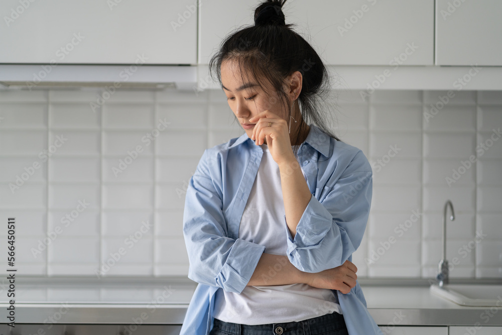 Offended embarrassed Asian woman looking down and feeling sad after