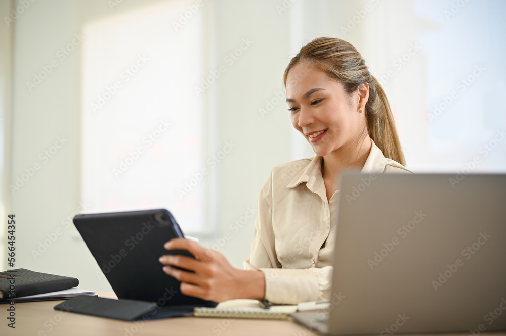 Attractive Asian businesswoman examining presentation slides on tablet, using tablet at her desk. Attractive Asian businesswoman examining presentation slides on tablet, using tablet at her desk.