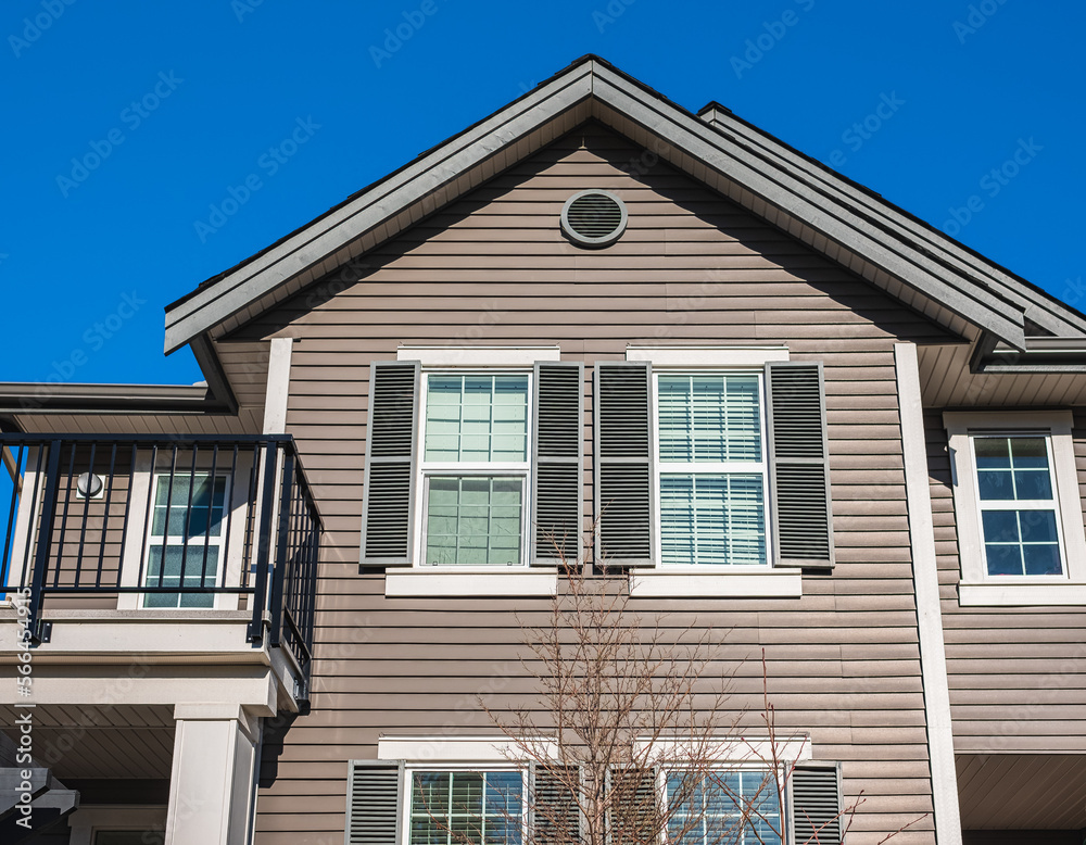 Top of a house with nice windows. Dormer and a blue sky. Real Estate Exterior Front House in a residential neighborhood