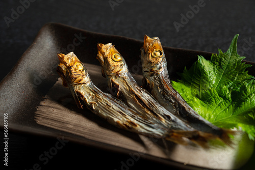 Grilled urume sardines on a black table. A side dish of sake. photo