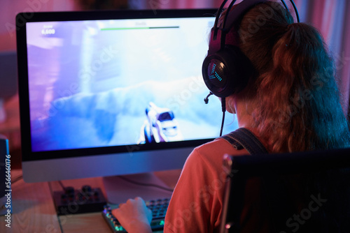 Obraz na plátně Girl in headset playing first person shooter, view over shoulder