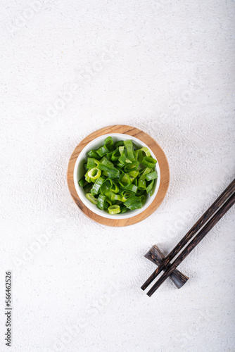 Chopped spring onion in white bowl on white concrete. Ingredients food.