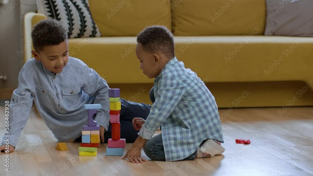 Cute happy african american brothers playing together at home, building towers with wooden blocks and laughing Cute happy african american brothers playing together at home, building towers with wooden blocks and laughing
