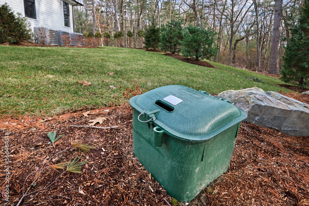 Underground propane tank dome in the front flowerbed of a suburban home