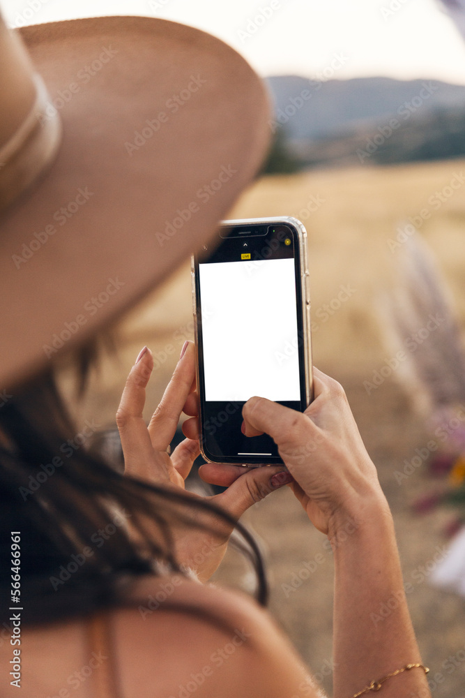 Woman in hat holds cell phone in the field