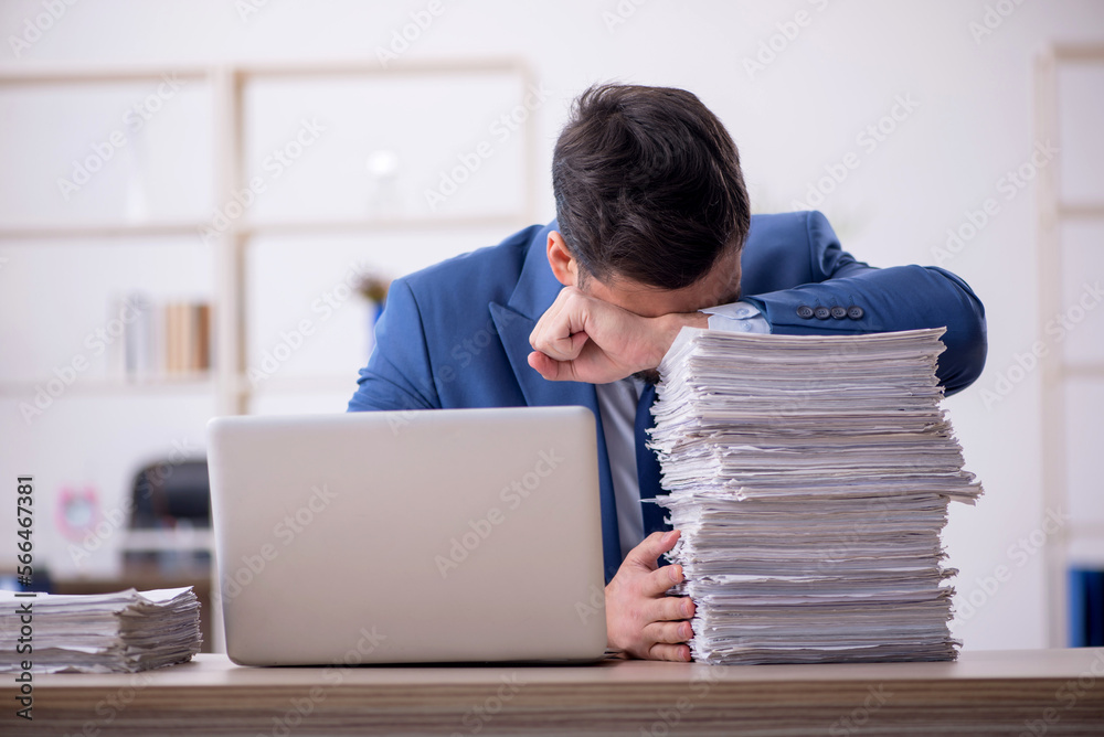 Young male employee and too much work in the office Young male employee and too much work in the office