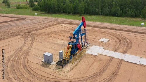 Oil rig pump rocking chair against the background of the autumn forest. Extraction of oil from a well using a pump.  oil pumping stations pump jacks in a clearing in the forest photo