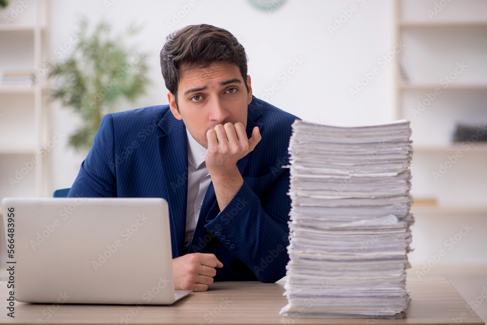Young male employee and too much work in the office Young male employee and too much work in the office
