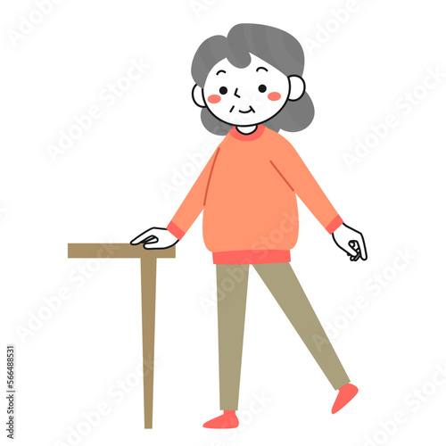 机につかまって片足立ちの運動をするシニア女性